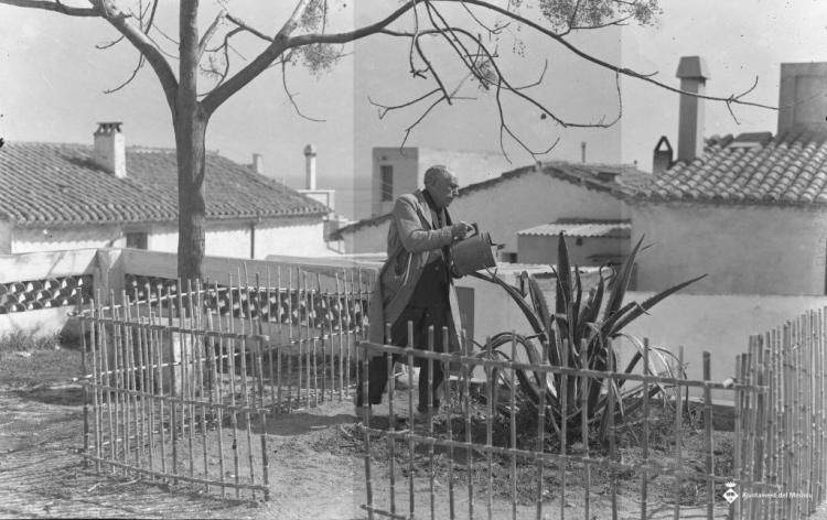 Un home regant una planta al carrer de la Caterra?
