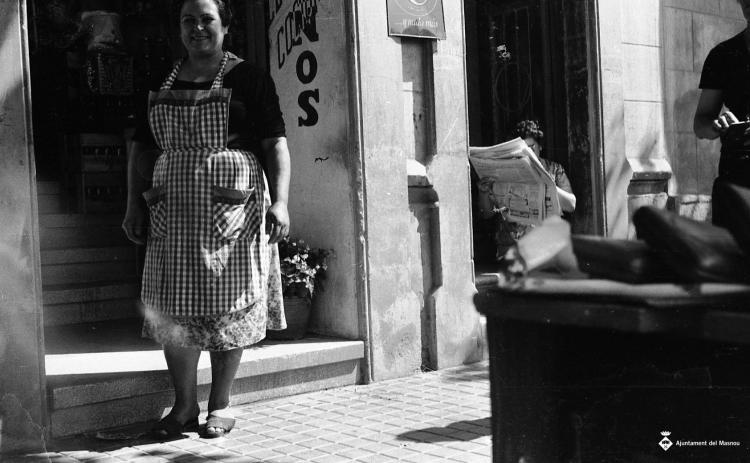 Dona sortint d'una botiga i altra llegint el diari