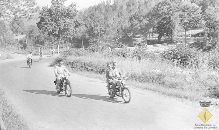 Grup de jove en bicicleta i motocicleta per l'actual carretera BV-2421 el dia de la visita del bisbe de Barcelona