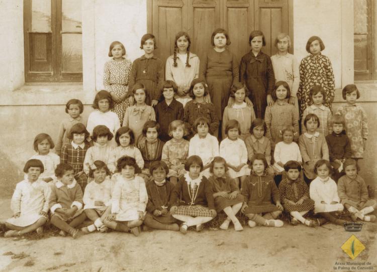 Grup escolar femení davant de la porta de l'escola