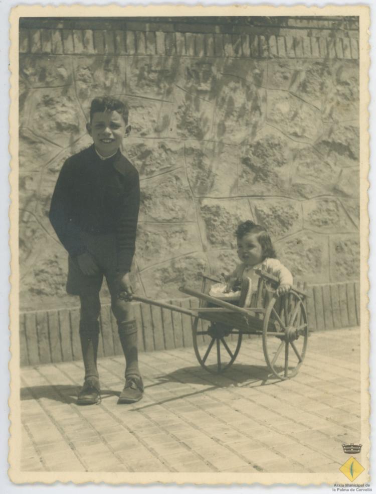 Miquel Albertí i Rosa Albertí en un carret i amb una mona a la vorera davant les antigues torres del Puig, a l'actual avinguda Catalunya
