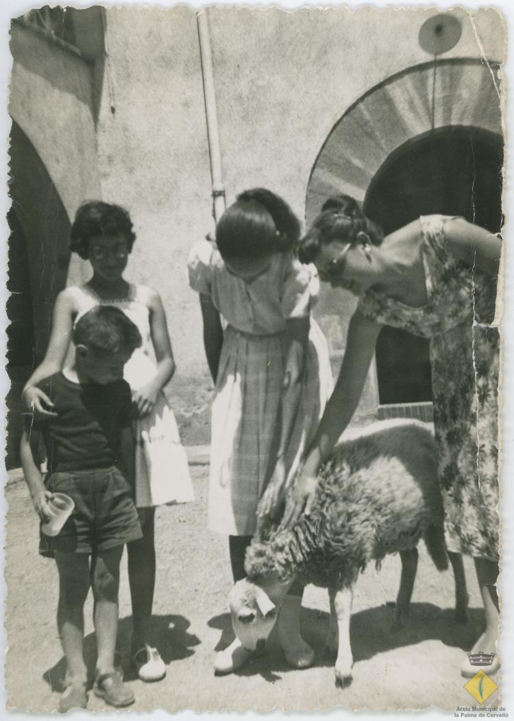 Tres dones i un nen amb un xai davant de Ca n'Iglésies