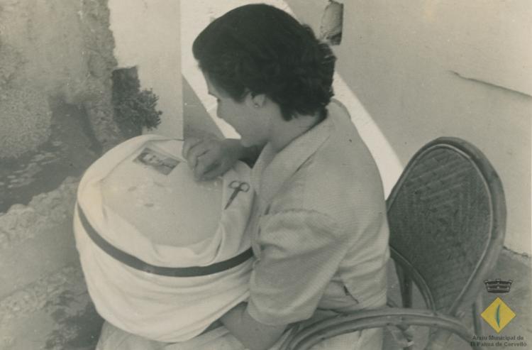 Montserrat Rigol brodant un joc de taula amb la fotografia de la seva parella sobre el bastidor