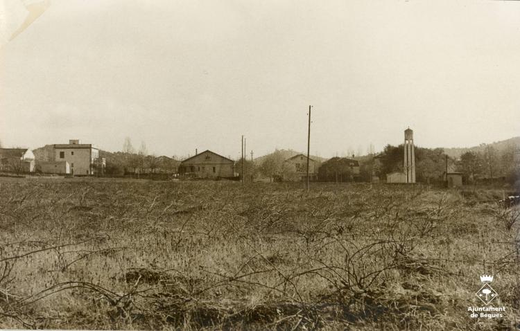 Vista de la zona on actualment hi ha el carrer Ferran Muñoz amb el pou d'aigua al fons i vinyes en primer terme
