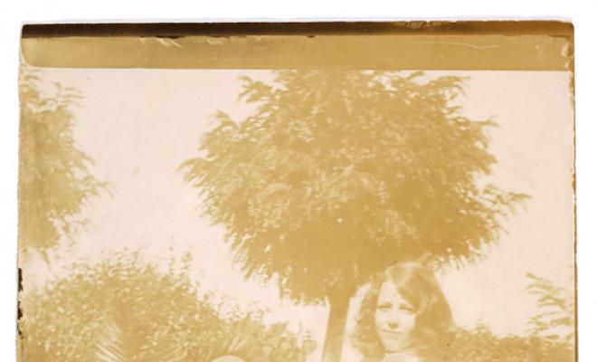 Nena amb un salabre en un jardí. S.l.