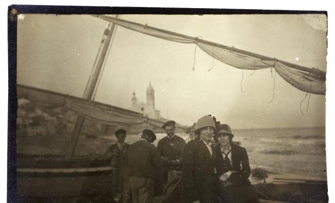 Retrat de dues noies assegudes sobre una barca de pescadors a la platja de Sitges.