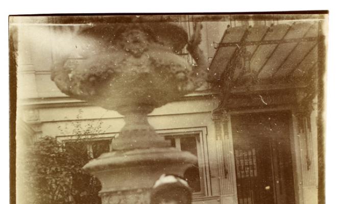 Dona davant d'un jerro decoratiu a l'exterior d'un edifici. S.l.