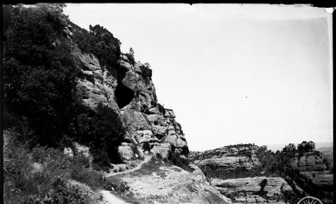 Camí d'accés i diaclassa de la cova Simanya. Al fons els Emprius. Parc Natural de Sant Llorenç del Munt