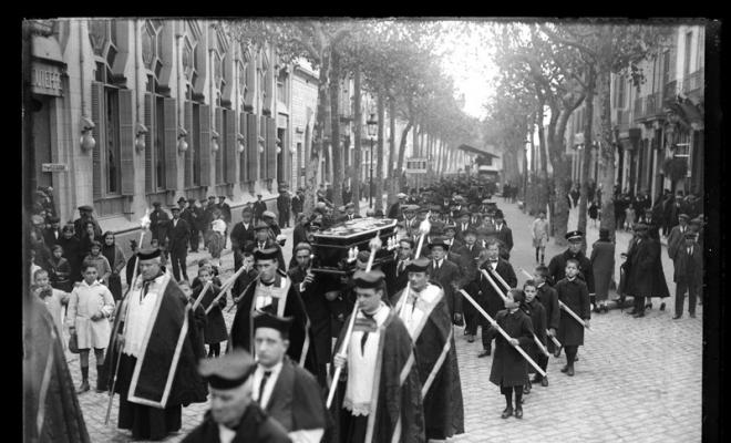 Enterrament de Josep Gorina Pujol. Clergues de la Santíssima Trinitat i el fèretre portat a hombros a la Rambla de Sabadell al seu pas pel teatre Euterpe. Sabadell