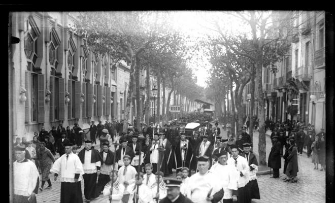 Enterrament de Josep Gorina Pujol. Clergues de la Santíssima Trinitat i el fèretre portat a les espatlles per la Rambla de Sabadell al seu pas pel teatre Euterpe. Sabadell