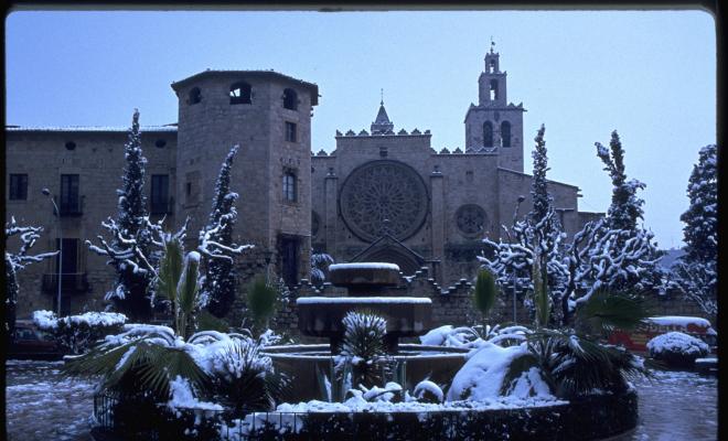 Font de la plaça d'Octavià coberta de neu, al fons, l'església de Sant Pere d'Octavià. 