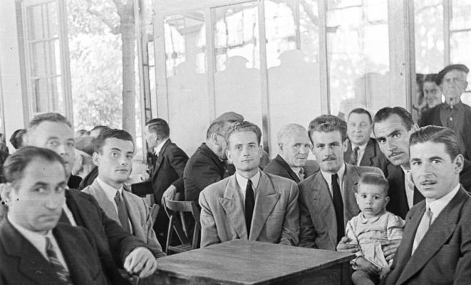 Actes de la festa inaugural de la restaurada Societat Coral La Unió Santcugatenca. Jaume Grau assegut amb un grup d'homes i un infant, a la sala del cafè de la Unió.
