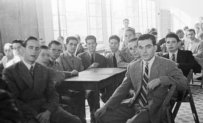 Actes de la festa inaugural de la restaurada Societat Coral La Unió Santcugatenca. Un grup de joves asseguts, a la sala del cafè de la Unió.