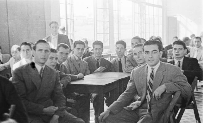 Actes de la festa inaugural de la restaurada Societat Coral La Unió Santcugatenca. Un grup d'homes asseguts a la sala del cafè de la Unió.