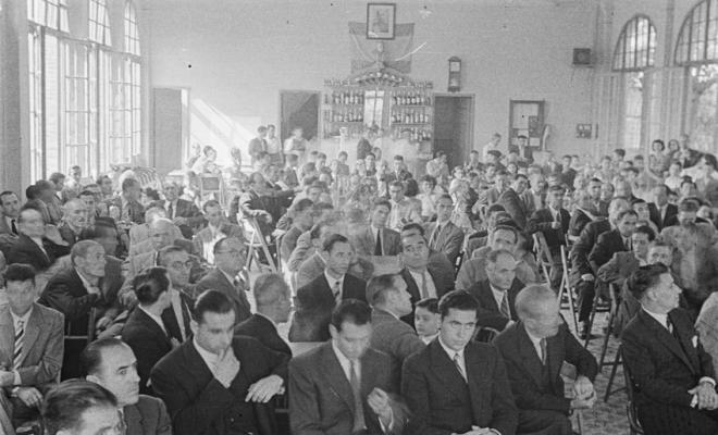 Actes de la festa inaugural de la restaurada Societat Coral La Unió Santcugatenca. Benedicció del local. Assistents a la sala del cafè de la Unió.