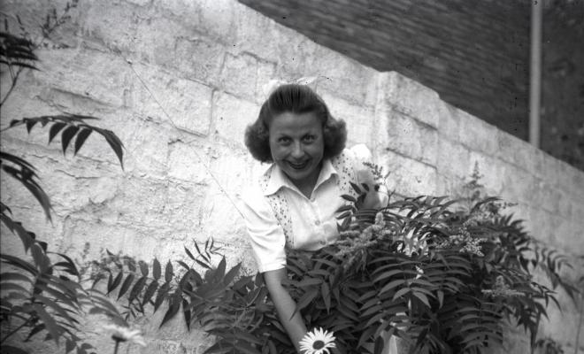 Dona retratada, mostrant una flor, al pati del fotògraf.