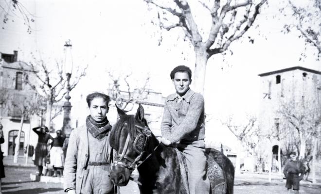 Tres Tombs, retrat de dos nois, un d'ells muntant un ruc, a la plaça d'Octavià.