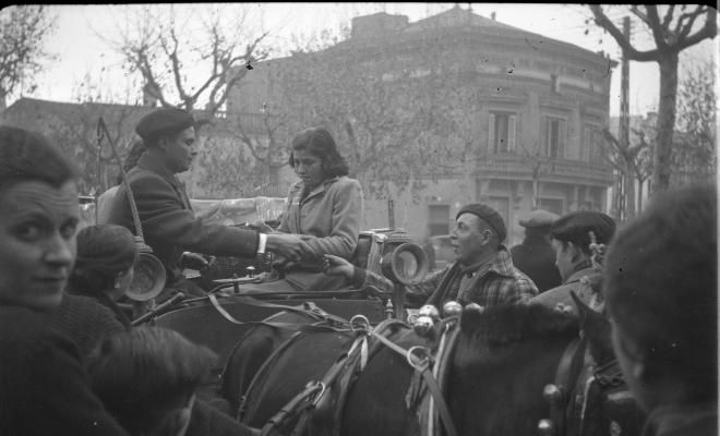 Festa de Sant Antoni Abat. Una noia en un carruatge, al fons l'edifici de Cal Gerrer.
