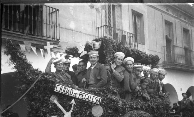 Festa de Sant Antoni Abat. Carruatge enramat amb forma de vaixell, amb el rètol: Ciutat de Regalèssia, amb els membres de la Penya Regalèssia vestits de mariners durant la passada.