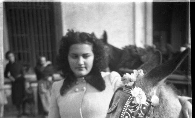 Festa de Sant Antoni Abat. Retrat d'una noia davant d'un ruc d'un dels carros al seu pas per la plaça de Barcelona.