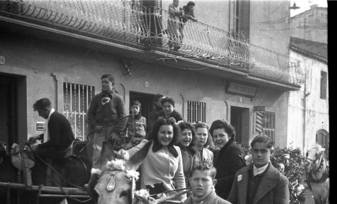 Festa de Sant Antoni Abat. Retrat de un grup de joves dalt d'un carro al seu pas per la plaça de Barcelona.