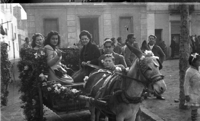 Festa de Sant Antoni Abat. Retrat de un grup de joves dalt d'un carro al seu pas per la plaça de Barcelona.