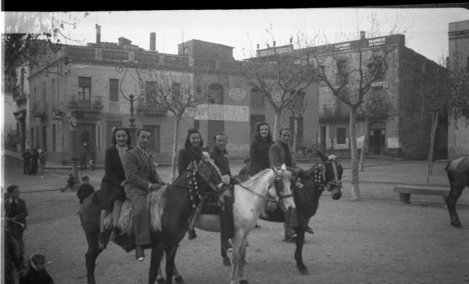 Festa de Sant Antoni Abat. Retrat  de tres parelles  joves muntant a cavall, a la plaça d'Octavià, prop del brollador de benzina i del carrer Major.