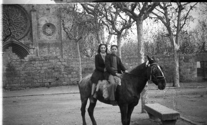 Festa de Sant Antoni Abat. Retrat d'un jove muntant i una dona a cavall a la plaça d'Octavià.