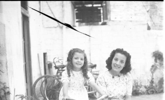 Retrat de l'Elisabet  Cabanas sobre una bicicleta i de la Maria Quiñonero asseguda sobre el sidecar de vímet.
