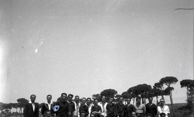 Activitats festives. Retrat dels components dels equips de futbol. Ubicació no identificada, a prop hi ha una catenària d'un tren.