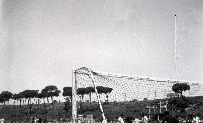 Activitats festives, partit de futbol. Ubicació no identificada, a prop hi ha una catenària d'un tren.