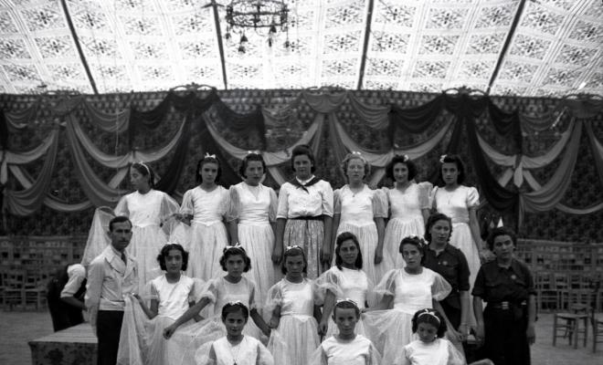 Festa Major. Ball a l'envelat, retrat d'un grup de nenes, probablement de la secció infantil de l'Esbart Dansaire, acompanyades per  Manuel Farrés i dues dones uniformades.