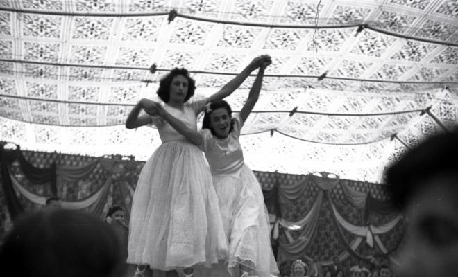 Festa Major. Noies ballant a l'escenari de l'envelat, probablement de la secció infantil de l'Esbart Dansaire, acompanyades per  Manuel Farrés i dues dones uniformades.