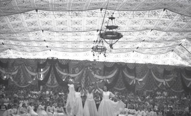 Festa Major. Noies ballant a l'escenari de l'envelat, probablement de la secció infantil de l'Esbart Dansaire, acompanyades per  Manuel Farrés i dues dones uniformades.