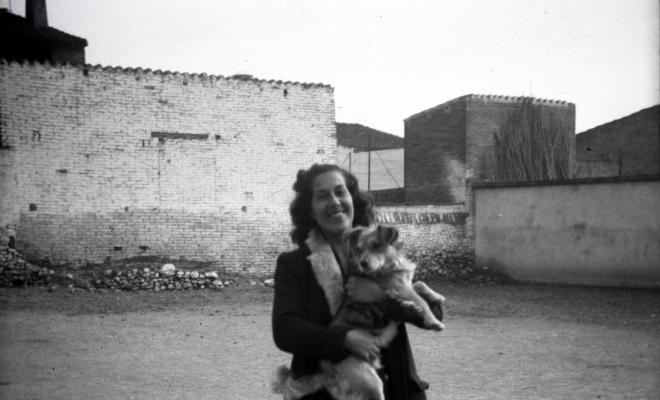 Celebració davant de la seu de la Falange a Cal Barbany. Retrat d'una noia amb un gos en braços, a la plaça del Quatre Cantons.