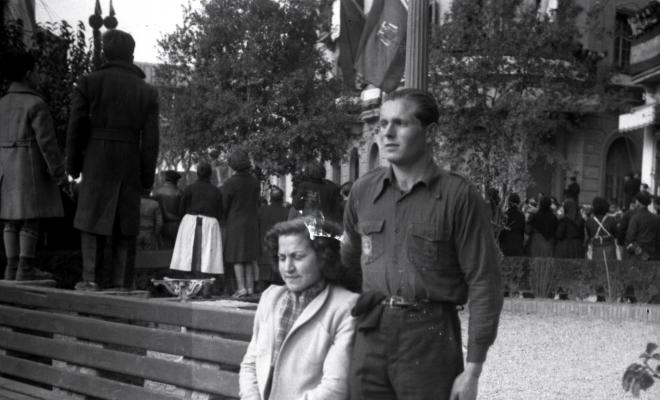 Celebració davant de la seu de la Falange a Cal Barbany.Retrat d'una parella, al fons el públic d'esquena a l'escena assisteix a la desfilada davant de la seu de la falange.
