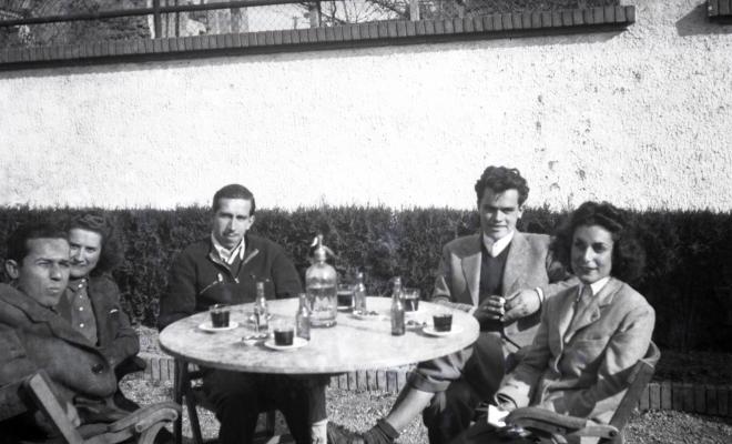 Celebració davant de la seu de la Falange a Cal Barbany. Retrat d'uns joves asseguts en una de les taules del quiosc de la plaça dels Quatre Cantons.