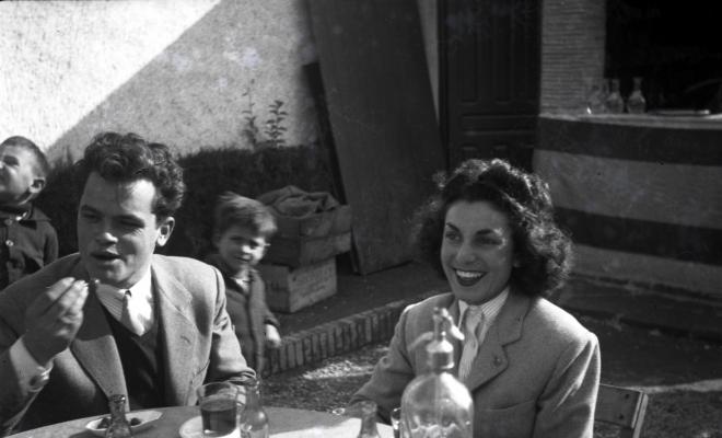 Celebració davant de la seu de la Falange a Cal Barbany. Retrat d'uns joves asseguts en una de les taules del quiosc de la plaça dels Quatre Cantons.