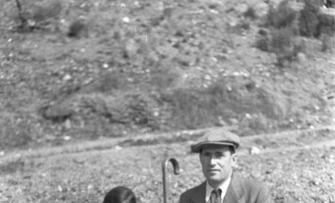 Aplec de Sant Medir. Retrat d'una nena i un home asseguts a terra.