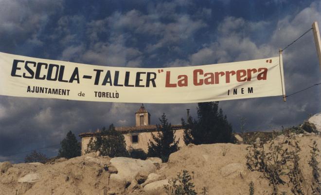 Edifici de la Carrera amb cartell de l'Escola-Taller La Carrera 