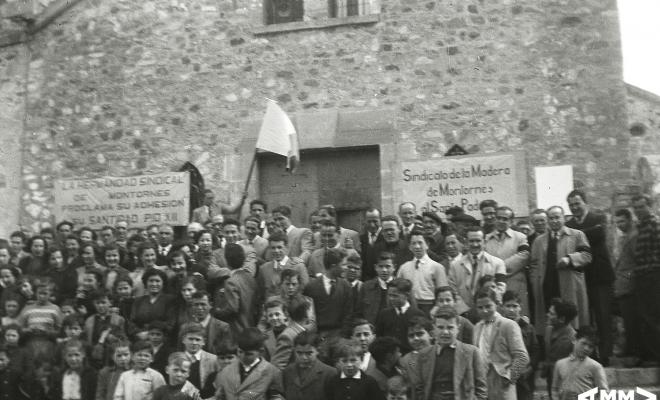 Grup de persones a les escales de l'església amb una bandera