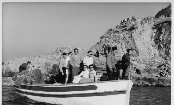 Barca de pesca arribant a la platja de Tossa de Mar carregada de gent