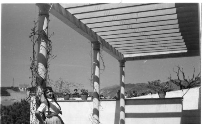Nena recolzada a la columna d'una pèrgola d'una torre d'estiueig