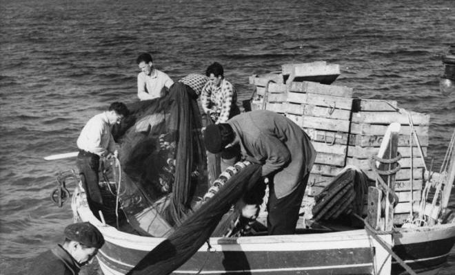 Pescadors descarregant les xarxes des de una barca