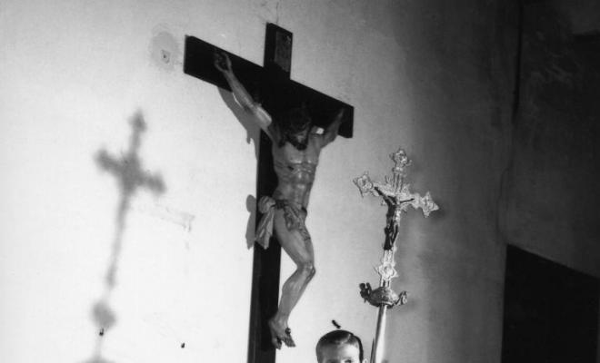 Nen vestit d'escolà amb una creu a les mans