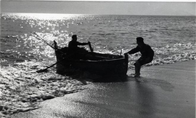 Un home varant una barca de rems a la platja del Masnou