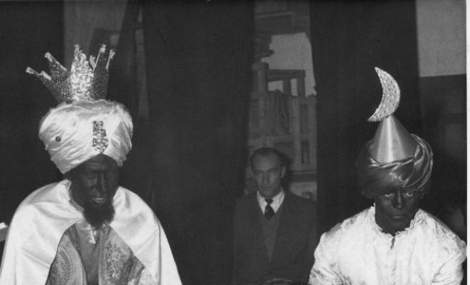 Nen sostenint un regal acompanyat de dos patges la nit de reis