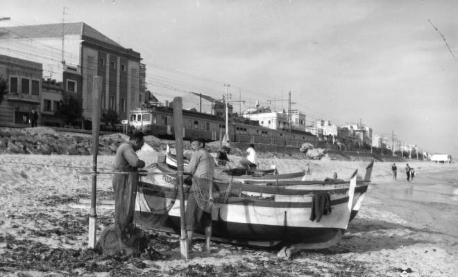 Pescadors treballant al costat de les barques varades a la platja
