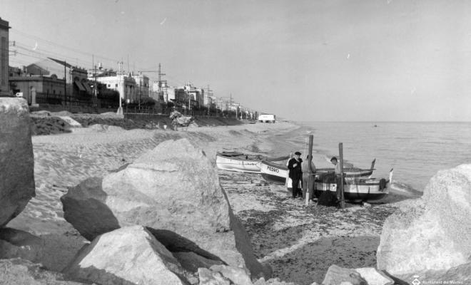 Tres homes al costat de les barques varades a la platja
