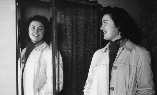 Una alumna de Teresa Torres provant-se un abric davant un mirall